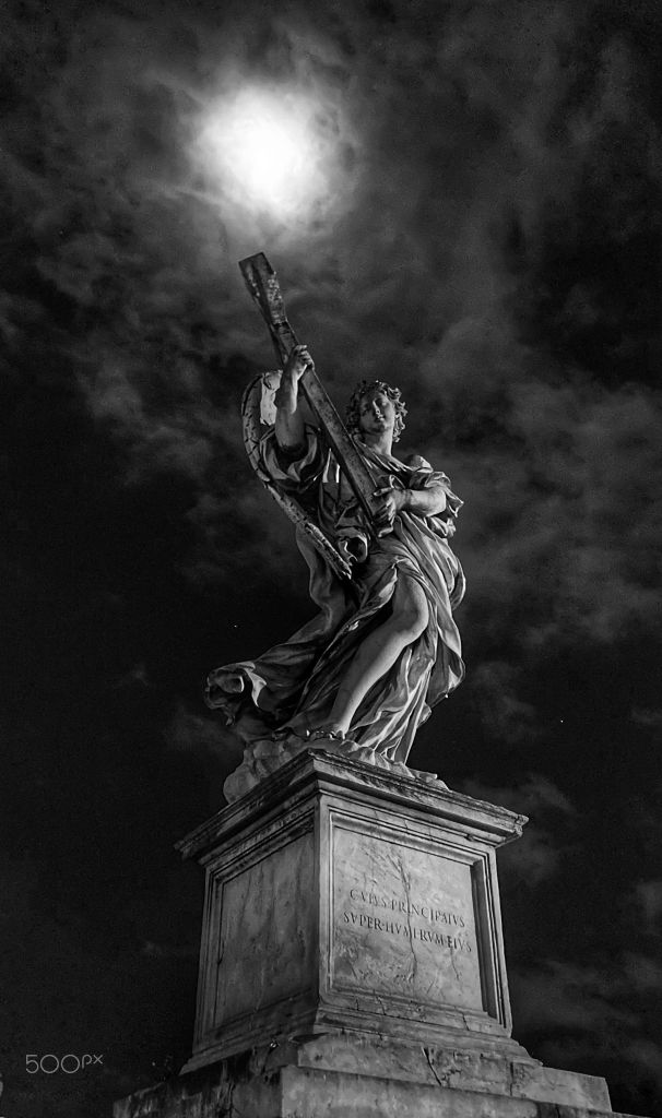 Statua di un angelo sotto un cielo nuvoloso, in bianco e nero